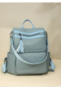 Detail view of light blue fashion backpack with woven texture and tassel accessory