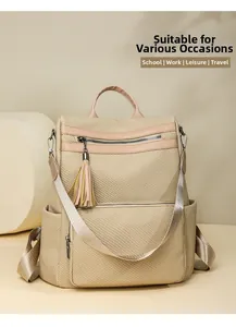 Detail of beige woven backpack with leather trim and tassel on a geometric stand