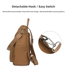 Detail of detachable metal hook on brown textured backpack for versatile carrying styles