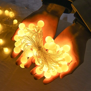 Warm white LED globe string lights held in hands for festive Christmas tree decoration