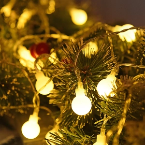 Warm white LED globe string lights on Christmas tree branches with frosted round bulbs