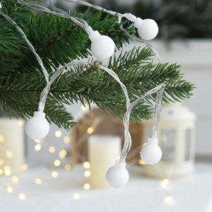 Warm white LED Christmas ball string lights hanging on a green festive pine tree