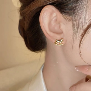 Gros plan d'une boucle d'oreille cheval à bascule dorée portée à l'oreille polie