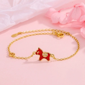 Elegant gold bracelet with red enamel horse charm and coin details on pink background