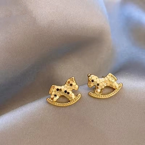 Détail macro de boucles d'oreilles cheval à bascule dorées avec une texture nid d'abeille