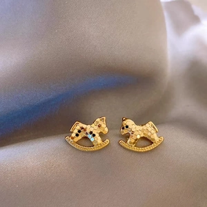 Boucles d'oreilles cheval à bascule dorées avec texture sur fond en soie douce