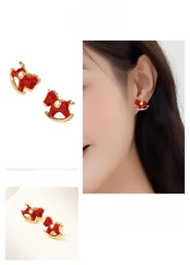 Detail of red enamel rocking horse earrings with gold star accent on model ear