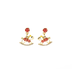 Macro detail of rocking horse earrings with red enamel and pavé zircon settings