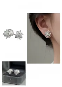Detail of silver firework-shaped pearl earrings with crystal accents and jewelry box
