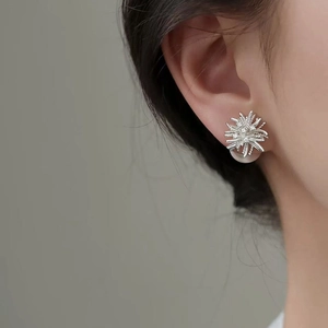 Macro shot of silver fireworks earrings with white zircon stones on model's earlobe