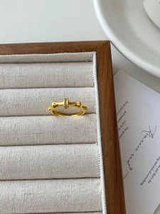 Detailed close-up of a golden bamboo style ring with a tiny zircon in a wooden box
