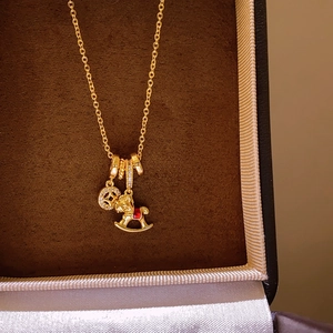 Golden necklace with micro-paved ring and rocking horse pendant with red accents