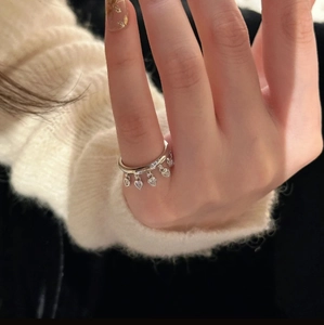 Minimalist silver ring with five dangling heart charms and crystals on knit background