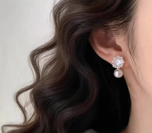 Close-up of elegant sparkling snowflake stud earrings with white pearl and zircon accents