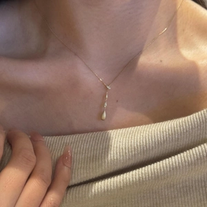 Elegante collana dorata con pendenti a goccia verticali indossata da una modella