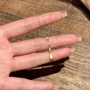 Primo piano della collana con pendente a goccia dorata con pavé lucido e finitura opaca