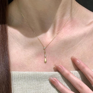 Elegante collana dorata a goccia con dettagli in zircone indossata da una modella