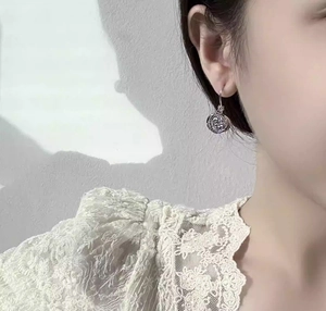 Close-up of elegant silver rose drop earrings with layered petals on a model