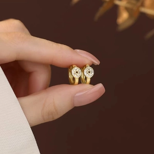 Elegant gold hollow coin hoop earrings with micro-paved zircons held by hand