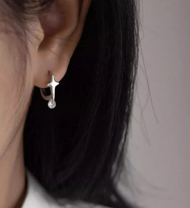 Close-up of silver star hoop earrings with round zircon drop on a model's ear
