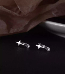 Detailed close-up of silver star earrings featuring cubic zirconia and north star motif