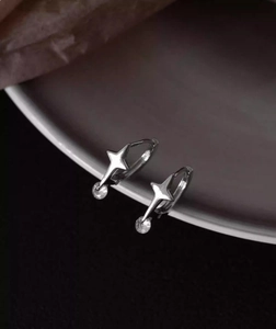 Macro shot of silver star huggie earrings with cubic zirconia charms on ceramic