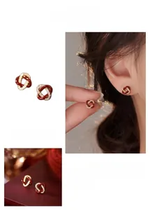 Gros plan sur des boucles d'oreilles nœud en émail rouge et zircons plaqués or