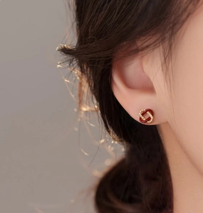 Gros plan sur des boucles d'oreilles nœud en émail rouge et or avec zircons