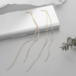 Detailed view of long gold linear fringe tassel earrings with delicate snake chain