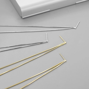 Close-up of minimalist gold and silver snake chain tassel drop earrings on a grey surface