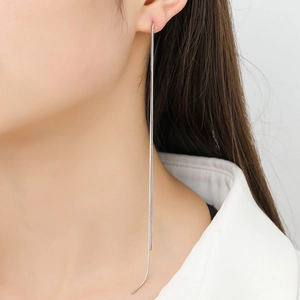 Detailed view of silver snake chain tassel earrings on model with elegant drape effect