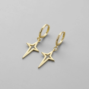 Macro detail of gold geometric cross star dangle earrings with polished mirror finish