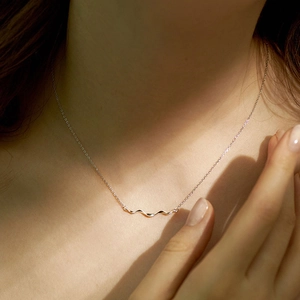 Minimalist silver wave pendant necklace shown on a model with elegant natural lighting