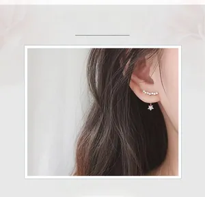 Close-up of sparkling star-shaped earrings with rhinestone-encrusted ear jackets on a model
