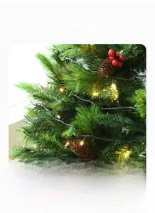 Detail of pine needles with red berries, pine cones and warm LED lights on a Christmas tree
