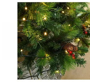 Close-up of Christmas tree featuring pine needles, warm LED lights, cones and red berries
