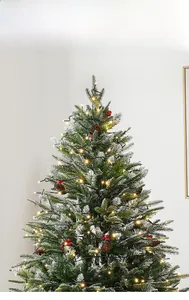 Detail of Christmas tree with dense snow-flocked PVC needles, pine cones, and red berries