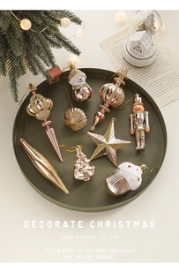 Detailed close-up of 9-piece rose gold Christmas ornaments with glitter in a green tray