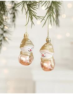 Close-up of sparkling champagne gold snowman ornaments hanging on a festive pine branch