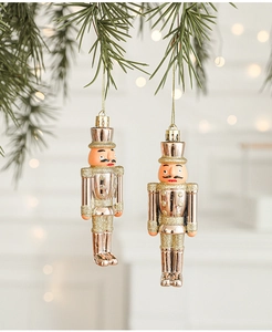 Detail of two gold Nutcracker soldier ornaments hanging on green pine branches