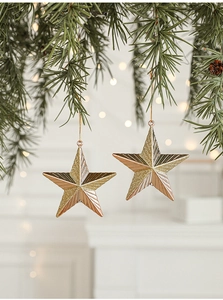 Close-up of glittery champagne and rose gold star ornaments hanging on a pine tree