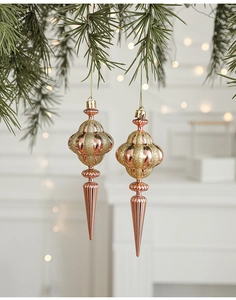 Close-up of rose gold Christmas tree pendants with gold glitter on pine branches