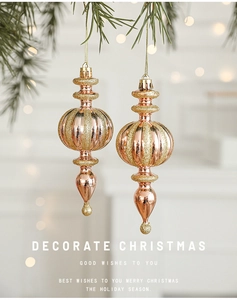Rose gold Christmas pendants with glitter stripes hanging on green pine branches