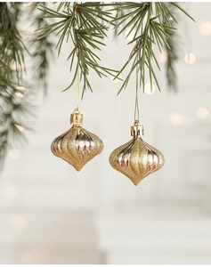 Close-up of golden onion-shaped Christmas ornaments with glitter hanging on pine branches