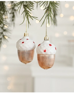 Close-up of rose gold acorn ornament with white snow finish hanging on a Christmas tree