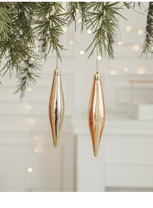 Detail of elegant rose gold and silver spindle Christmas ornaments hanging on a pine branch
