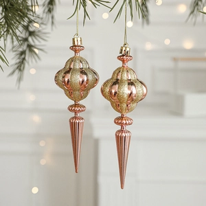 Rose gold Christmas tree ornaments with glitter stripes hanging on a pine branch