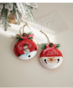 Detail of metal Christmas bells featuring snowman and Santa designs with pine cone accents