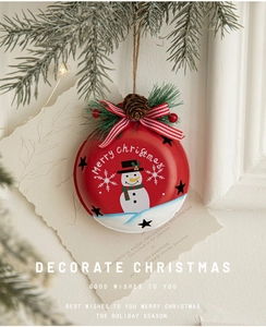 Close-up of red Christmas bell ornament with snowman motif, pine cones, and a striped bow