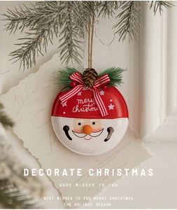 Detail of red and white metal Christmas bell with Santa face and pine cone ornament